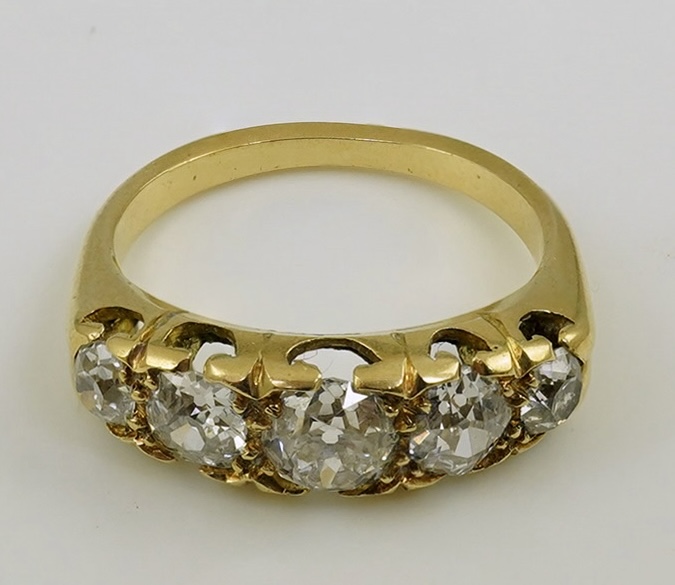 An antique gold and graduated five stone old mine cut diamond set half hoop ring